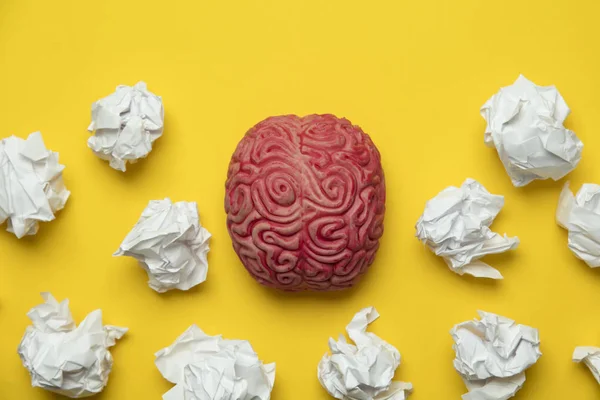 Ideas de lluvia de ideas. Cerebro con papel arrugado sobre un respaldo amarillo — Foto de Stock