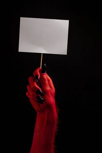 Рука червоного диявола тримає порожній білий знак. концепція Хеллоуїна — стокове фото