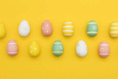 Parlak sarı bir arka plan üzerinde boyalı paskalya yumurtaları