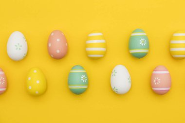 Parlak sarı bir arka plan üzerinde boyalı paskalya yumurtaları