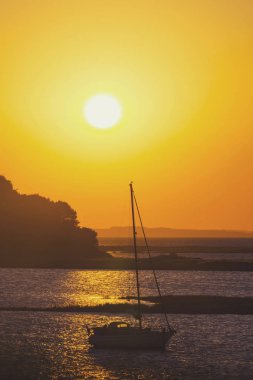 Güzel bir gün batımına karşı bir yelkenli yat silueti