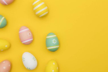 Parlak sarı bir arka plan üzerinde boyalı paskalya yumurtaları