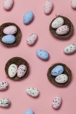 Pastel pembe arka plan üzerinde bir yuvada Paskalya yumurtaları
