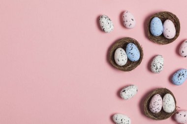 Pastel pembe arka plan üzerinde bir yuvada Paskalya yumurtaları