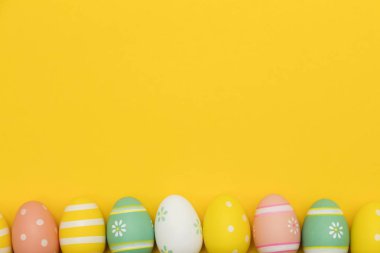 Parlak sarı bir arka plan üzerinde boyalı paskalya yumurtaları
