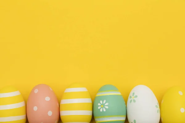 Malovaná velikonoční vajíčka na jasně žlutém pozadí — Stock fotografie