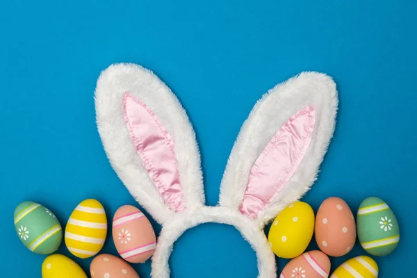 Easter holiday background with bunny ears and easter eggs on a b