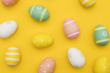 Parlak sarı bir arka plan üzerinde boyalı paskalya yumurtaları