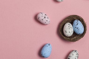 Pastel pembe arka plan üzerinde bir yuvada Paskalya yumurtaları