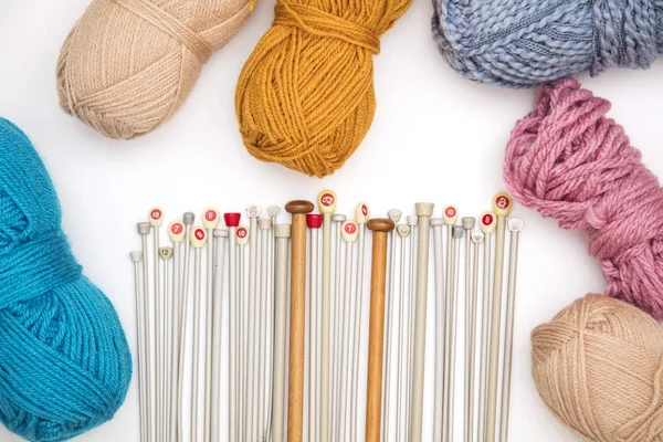 Collection of knitting needles and wool on a white background