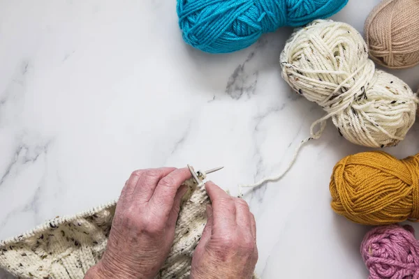 Senoir woman's hands knitting a jumper. Overhead view. — Stock Photo, Image