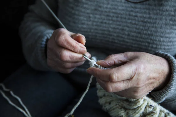 Close up of an older womens hands knitting a jumper Stock Photo