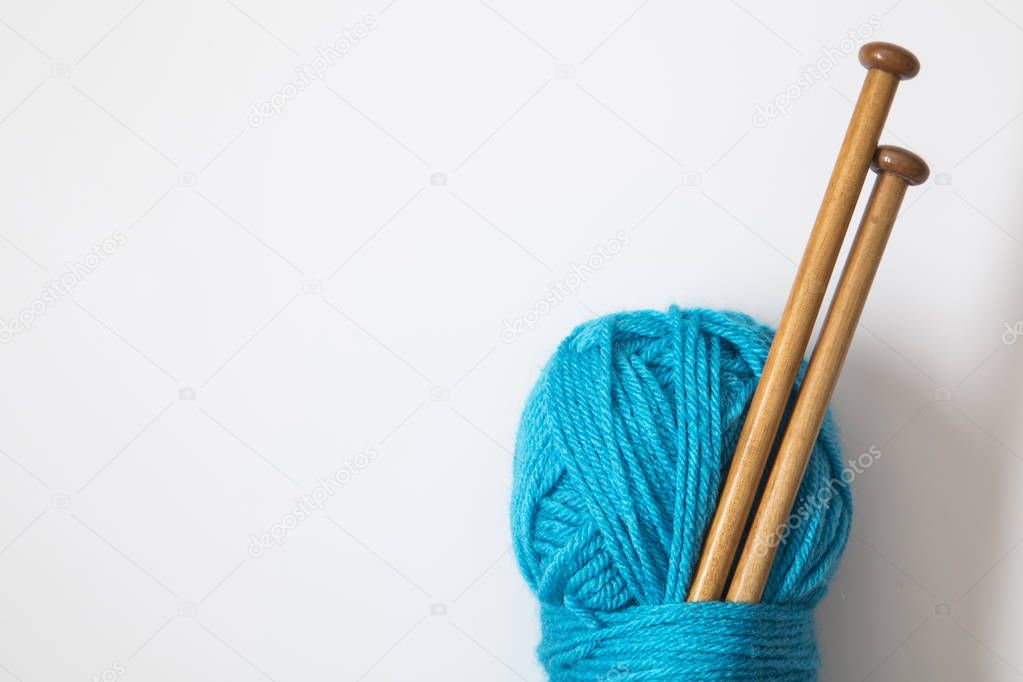 A ball of turquoise blue wool with wooden knitting needles
