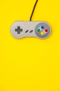 Parlak sarı arka planda Retro bilgisayar oyun denetleyicisi