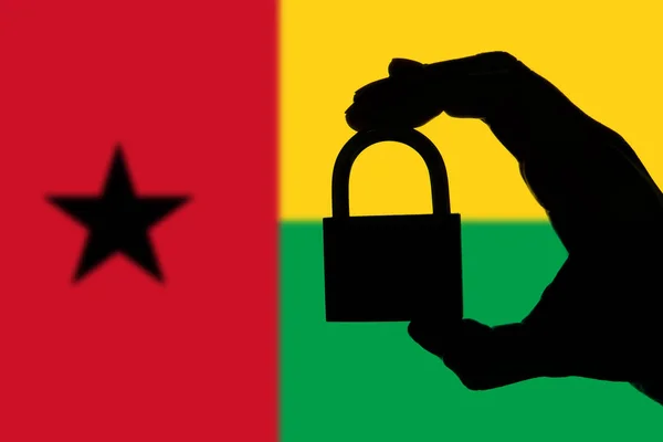 Seguridad de Guinea Bissau. Silueta de mano sosteniendo un candado ove — Foto de Stock