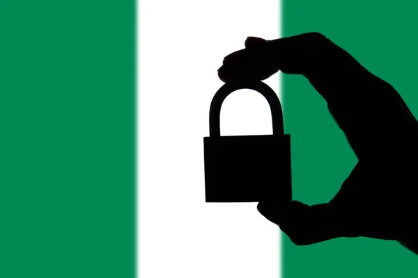 Seguridad de Nigeria. Silueta de mano sosteniendo un candado sobre nati — Foto de Stock
