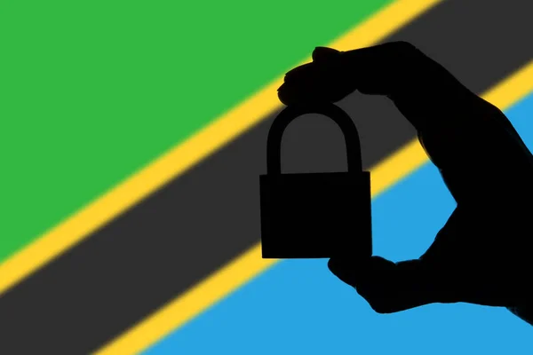 Tanzania security. Silhouette of hand holding a padlock over nat