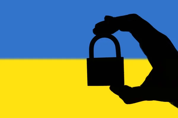 Sicherheit in der Ukraine. Silhouette der Hand hält ein Vorhängeschloss über nati — Stockfoto