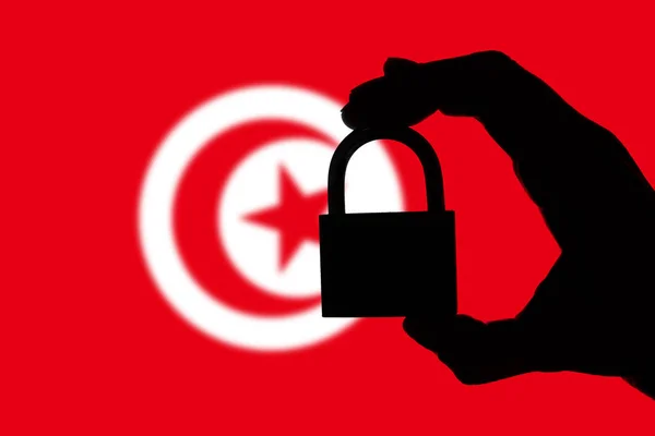 Tunisia security. Silhouette of hand holding a padlock over nati — Stock Photo, Image