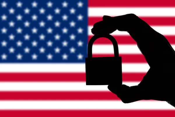 Bezpieczeństwo USA. Sylwetka dłoni trzymania kłódki nad narodowymi — Zdjęcie stockowe