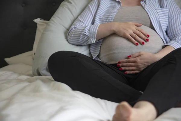 Eine junge schwangere Frau, die zu Hause auf einem Bett sitzt. werdende Mutter — Stockfoto