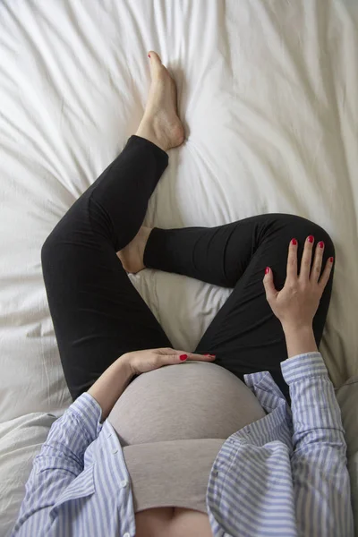 一个年轻的孕妇坐在家里，坐在床上。准妈妈 — 图库照片