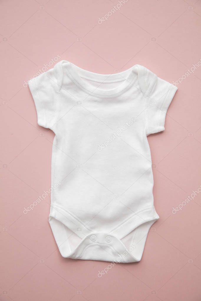 Cute baby white body suit layout on a pastel pink background