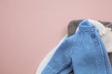 Pastel pembe arka plan üzerinde sevimli örme bebek kıyafetleri düzeni