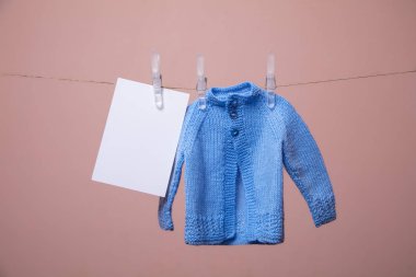 Örme bebek kazak ve boş kart bir giysi hattı üzerinde asılı