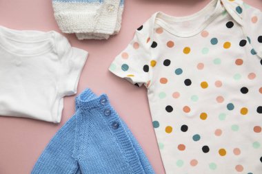 Pastel pembe arka plan üzerinde sevimli bebek kıyafetleri düzeni