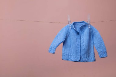 pembe karşı bir giysi hattı üzerinde asılı sevimli örme yeni doğmuş bebek jumper