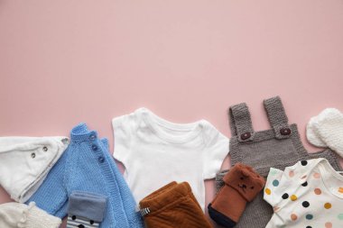 Pastel pembe arka plan üzerinde yenidoğan çocuk giyim düzeni