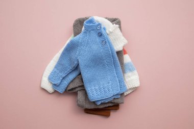 Pastel pembe arka plan üzerinde sevimli el yapımı örme bebek kıyafetleri düzeni