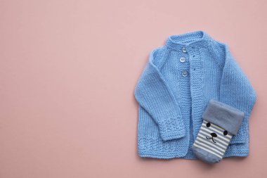 Pastel pembe arka plan üzerinde sevimli el yapımı örme bebek kıyafetleri düzeni