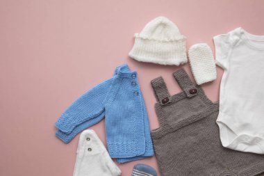 Pastel pembe arka plan üzerinde sevimli bebek kıyafetleri düzeni