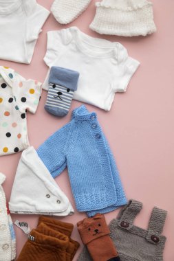 Pastel pembe arka plan üzerinde sevimli bebek kıyafetleri düzeni