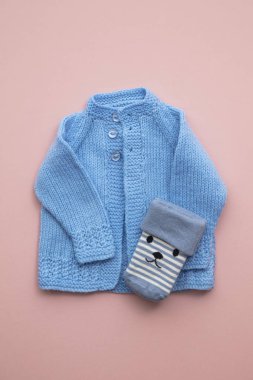 Pastel pembe arka plan üzerinde sevimli el yapımı örme bebek kıyafetleri düzeni