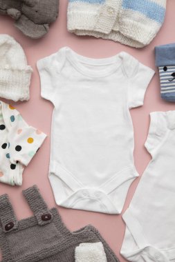 Pastel pembe arka plan üzerinde yenidoğan çocuk giyim düzeni