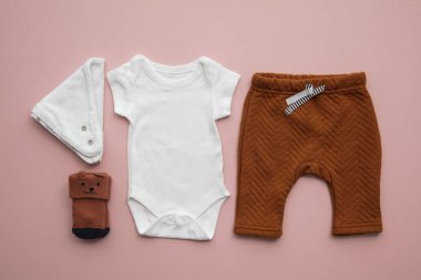Pastel pembe arka plan üzerinde yenidoğan çocuk giyim düzeni