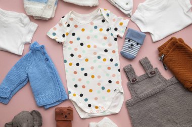 Pastel pembe arka plan üzerinde sevimli bebek kıyafetleri düzeni