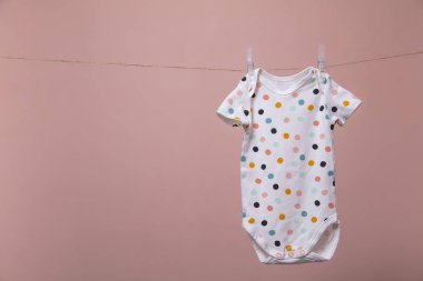 Sevimli polka nokta bebek vücut elbisesi pembe bir arka plan karşı bir çizgi asılı