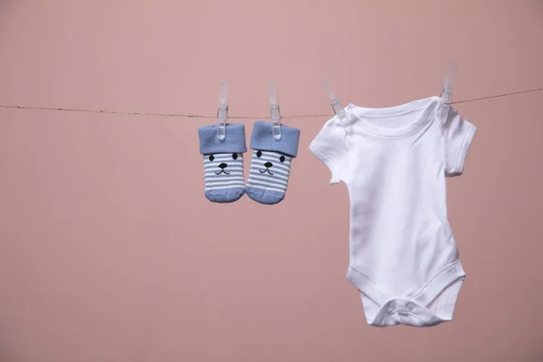 Costume bébé blanc suspendu à une ligne sur un fond rose — Photo