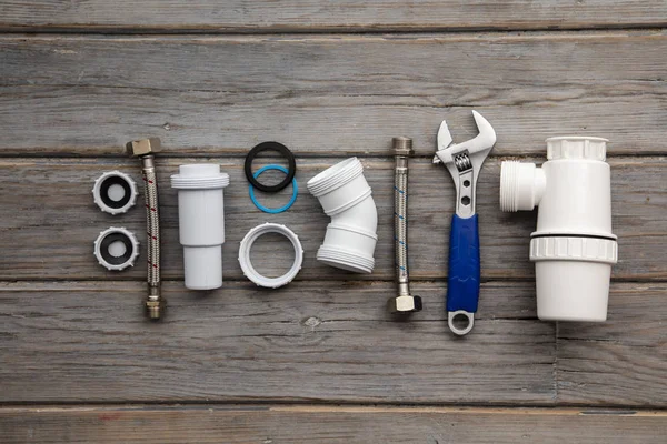 Sanitair gereedschap, pijp en bevestigingen op een rustieke houten achtergrond. Home Improvement — Stockfoto