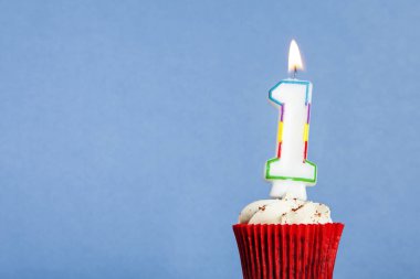 Mavi bir arka plan aleyhine bir cupcake içinde Number 1 doğum günü mum