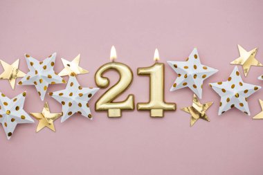 21 numara altın mum ve pastel pembe arka plan üzerinde yıldız