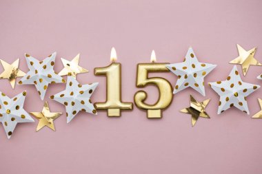 15 numara altın mum ve pastel pembe arka plan üzerinde yıldız