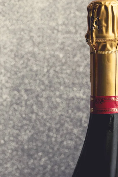Garrafa de champanhe em um fundo brilhante cintilante — Fotografia de Stock