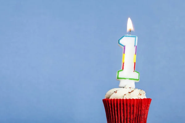 Número 1 vela de aniversário em um cupcake contra um fundo azul — Fotografia de Stock