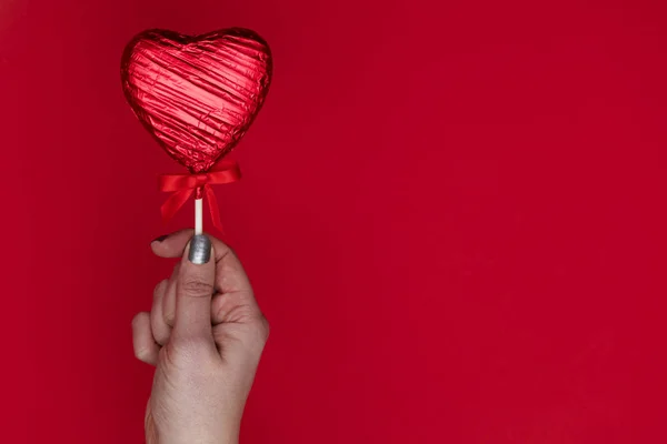 Valentines dag cadeau. Vrouwelijke hand houden een hartvormige loll a — Stockfoto