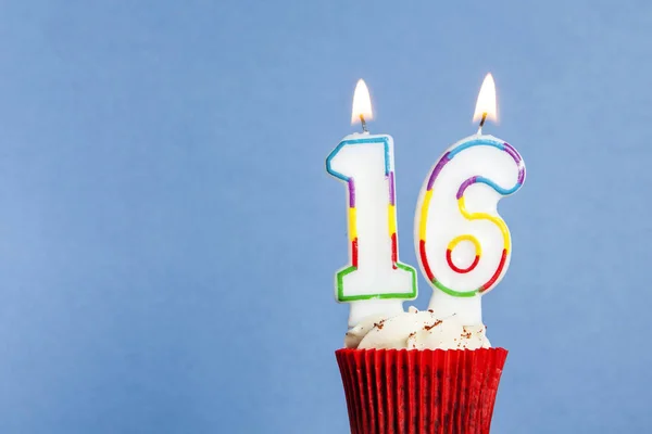 Número 16 vela de aniversário em um cupcake contra um fundo azul — Fotografia de Stock